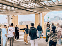 Teams gathering for the briefing in a shaded pavilion overlooking Dubai Creek