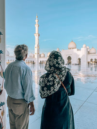 Guests looking out from the arcade over the courtyard and a minaret of Sheikh Zayed Grand Mosque