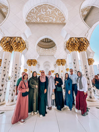 A group of guests under the gilded columns of the arcade at Sheikh Zayed Grand Mosque